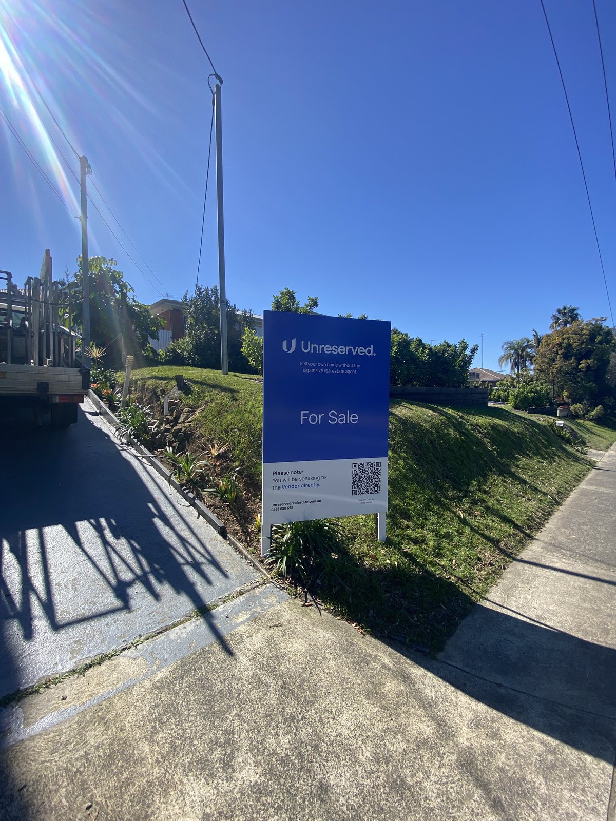 An upgraded Unreserved stock signboard installed on a nature strip outside a home